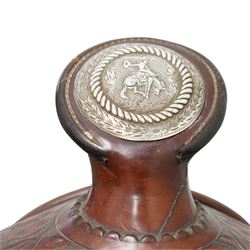 Keyston Bros (San Francisco) - 1930s/1940s 18’ American leather and silver mounted Western Parade saddle, the mahogany-tone leather body heavily hand-carved in a deep California Poppy floral pattern, surmounted by a ‘Bear Trap’ pommel fitted with an oval horn cap featuring a silver medallion of a cowboy on a bucking horse, further embellished with engraved sterling silver mountings, including large domed conchos, full-dress skirt corner plates, and a continuous cantle trim band, together with the associated girth, stirrups and leathers