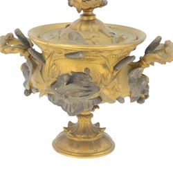 19th century gilt bronze twin handled urn, the removable cover with foliate decoration and finial modelled with a putti and swan, the body decorated in relief with swans and reeds, upon a circular foot, H19cm