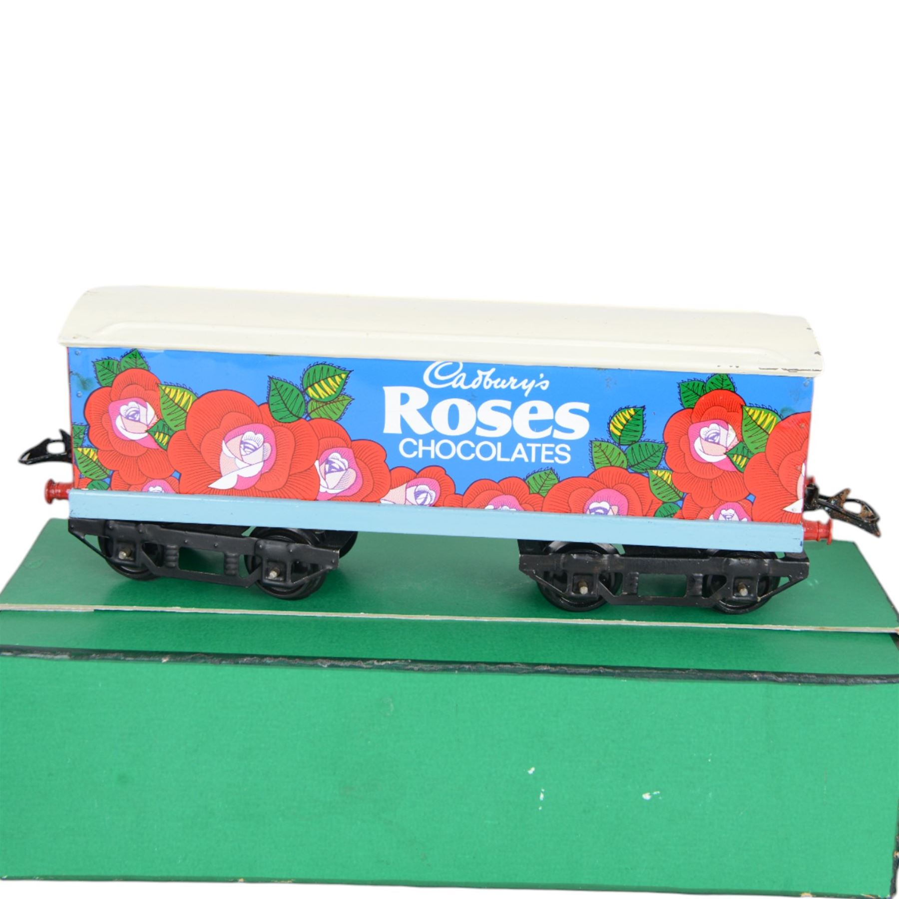 Three 0 gauge coaches, comprising an ACE Trains tin-printed All Third coach in LMS maroon livery, an ACE Trains tin-printed EMU MET 1st coach and a 'neverwazza' goods wagon, painted in Cadbury's Roses livery