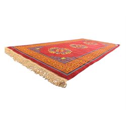 Tibetan-design handwoven rug, deep red field with three central medallions in yellow and blue, traditional yellow key border, white fringes on both ends