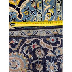 Central Persian Kashan hand-knotted carpet, the navy field with central medallion in pale blue and gold tones, surrounded by spiralling arabesques and palmettes, framed by quarter spandrels and a wide border of stylised lotus and rosette motifs between floral guard stripes, from the region of Kashan
