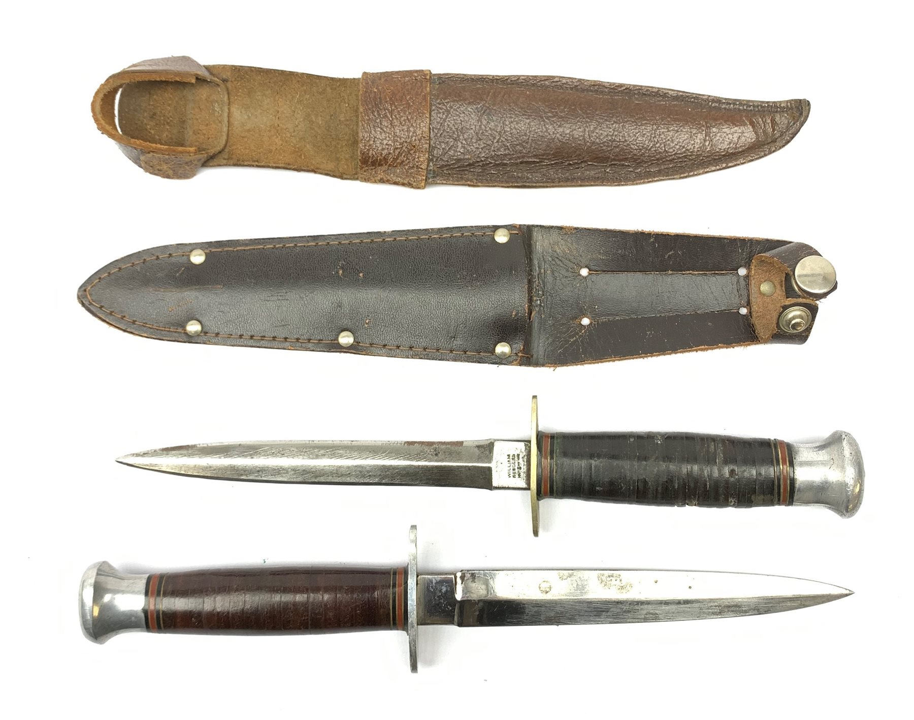 American WW2 type fighting knife the 15cm steel double edged blade marked to the ricasso William Rodgers Sheffield England, nickel crosspiece, leather bound grip and aluminium pommel L27cm overall; and another similar fighting knife with aluminium crosspiece; both in leather sheath (2)