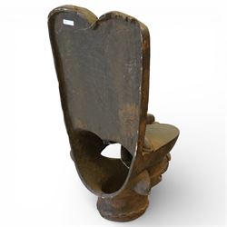 African carved hardwood ceremonial seat, monoxylous construction with twin dished seat wells, the tall back incised with repeating geometric triangular motifs, the front carved in the form of a tribal mask with projecting features, raised on a cylindrical base with ribbed and textured carving
