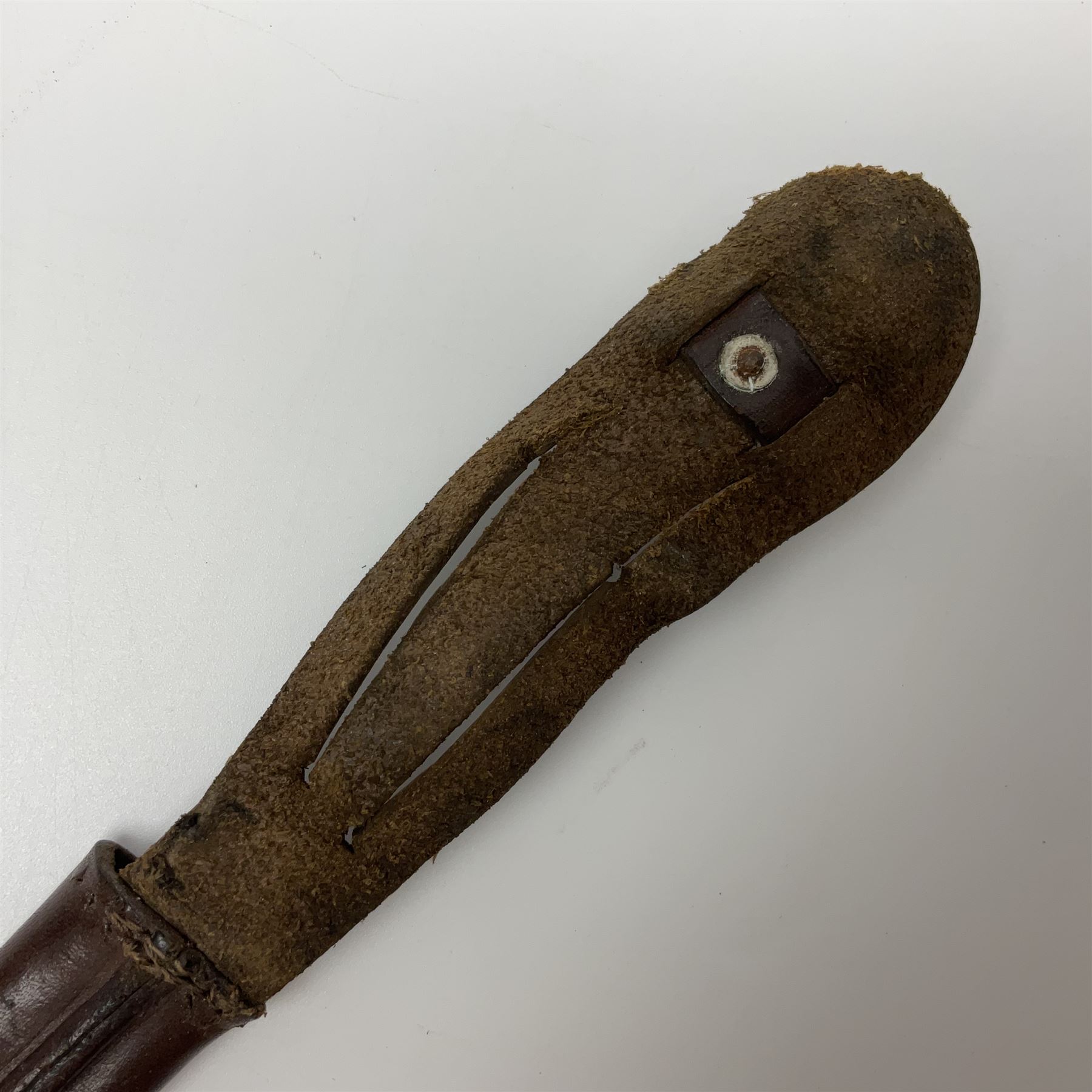 First Pattern Fairburn Sykes ''F-S'' Fighting Knife by Wilkinson Sword Ltd., the 17cm double edge steel blade with raised medial ridge to each side, each side of the ricasso with a recessed panel, one side with maker's name, the opposing side etched THE F~S FIGHTING KNIFE, with nickel plated brass recurving crossguard and diamond cut grip; in leather scabbard with metal chape