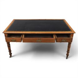 Victorian pitch pine writing table with leather inset top, rectangular top with three frieze drawers, pierced brass handles, raised on turned and fluted supports terminating in castors