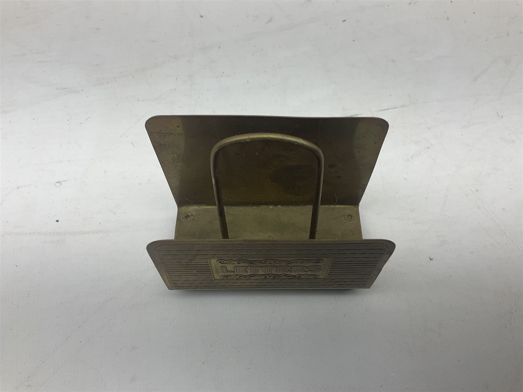 Collection of victorian and later brass desk accessories, to include a letter holder with cherub design, ink well of square form with hinged lid, brass table bell, brass casket with relief decoration, etc  