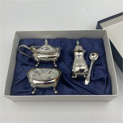 Modern silver plated three piece cruet set, comprising pepper shaker, open salt and mustard pot and cover, with two matching spoons, all of oval form with shaped rims and upon four pad feet, boxed
