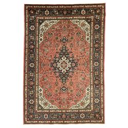 North West Persian pink ground Tabriz carpet, central indigo ground medallion surrounded by stylised plant motifs and trailing foliage, the main border with overall floral design within guard stripes 