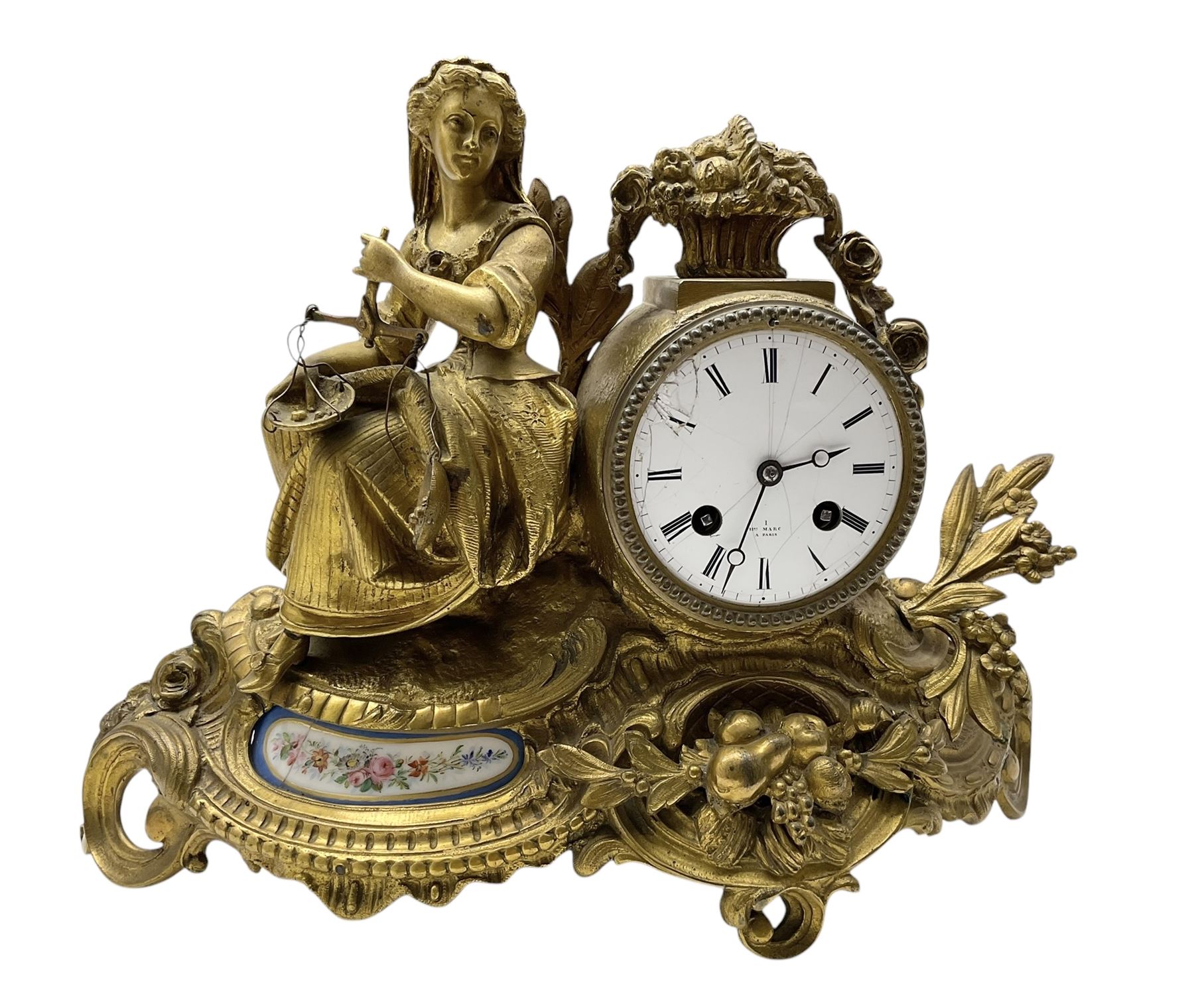 French-Gilt-metal mantle clock c1870, with a seated figure of a lady holding a pair of scales, on a scroll base with a porcelain panel on a blue ground depicting a floral spray of flowers, with brass castings of fruit and foliate decoration, enamel dial signed Henry Marc, Paris, with Roman numerals and steel moon hands, twin train countwheel striking movement sounding the hours and half-hours on a bell. With pendulum and key.