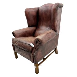 Georgian style wingback armchair, upholstered in leather with studded detail, on square moulded supports joined by plain stretchers 