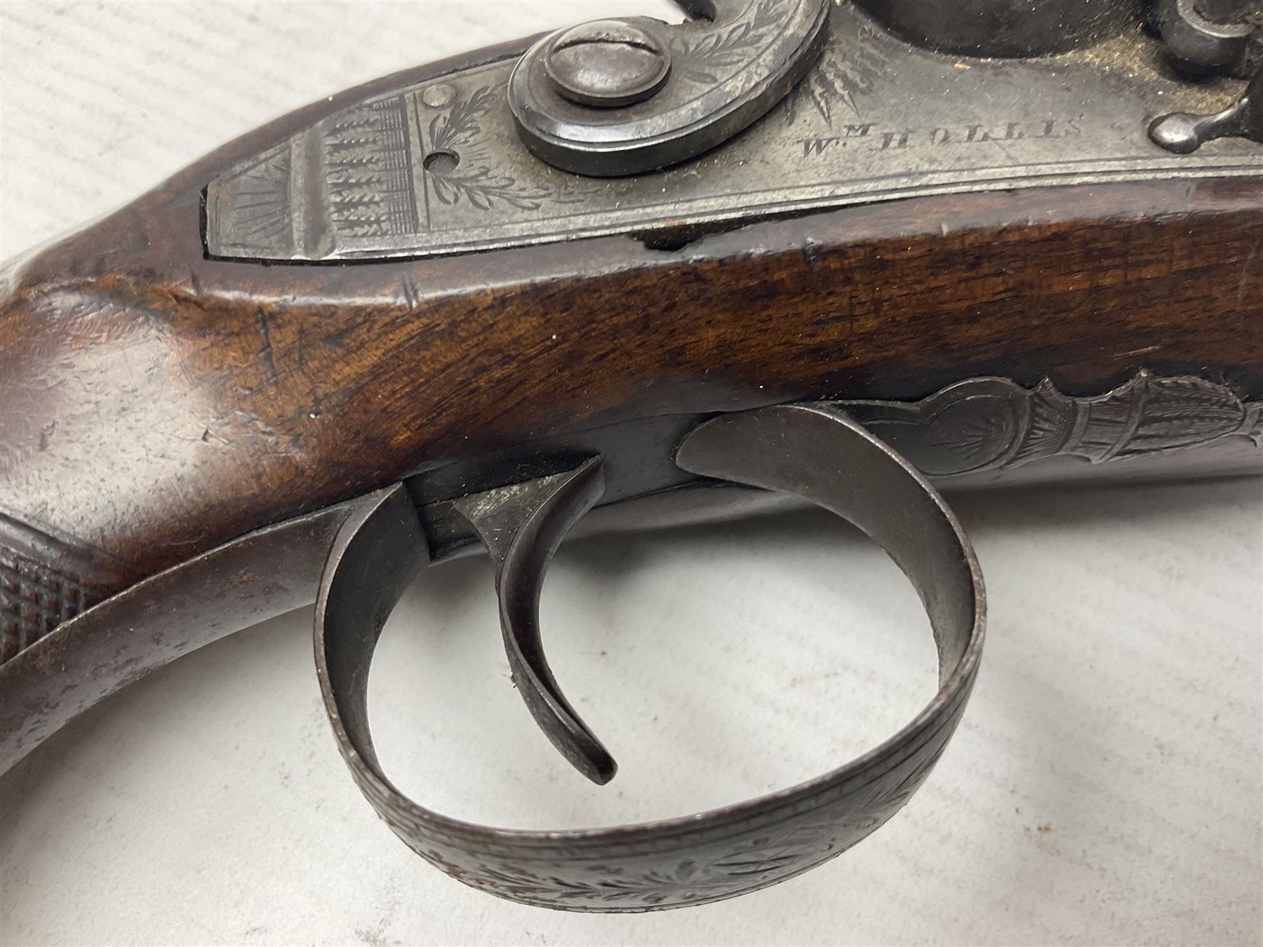 Early 19th century Wm. Hollis flintlock belt or pocket pistol, approximately 20 bore, the 10cm barrel with ram rod under, engraved lock plate with maker's name and roller frizzen, engraved trigger guard with pineapple finial and walnut stock with chequered grip L25cm overall