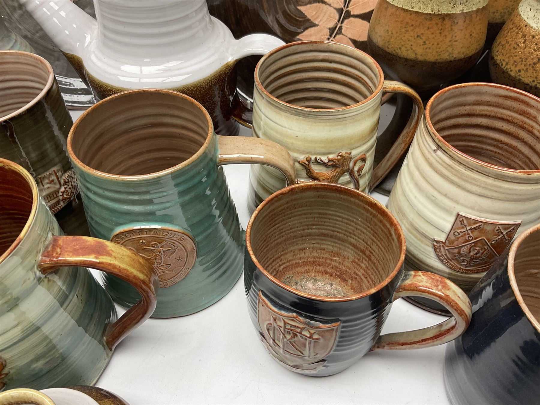 Wold studio pottery tankards, in various colours and relief decoration together with other studio items including vases, jugs and pots 