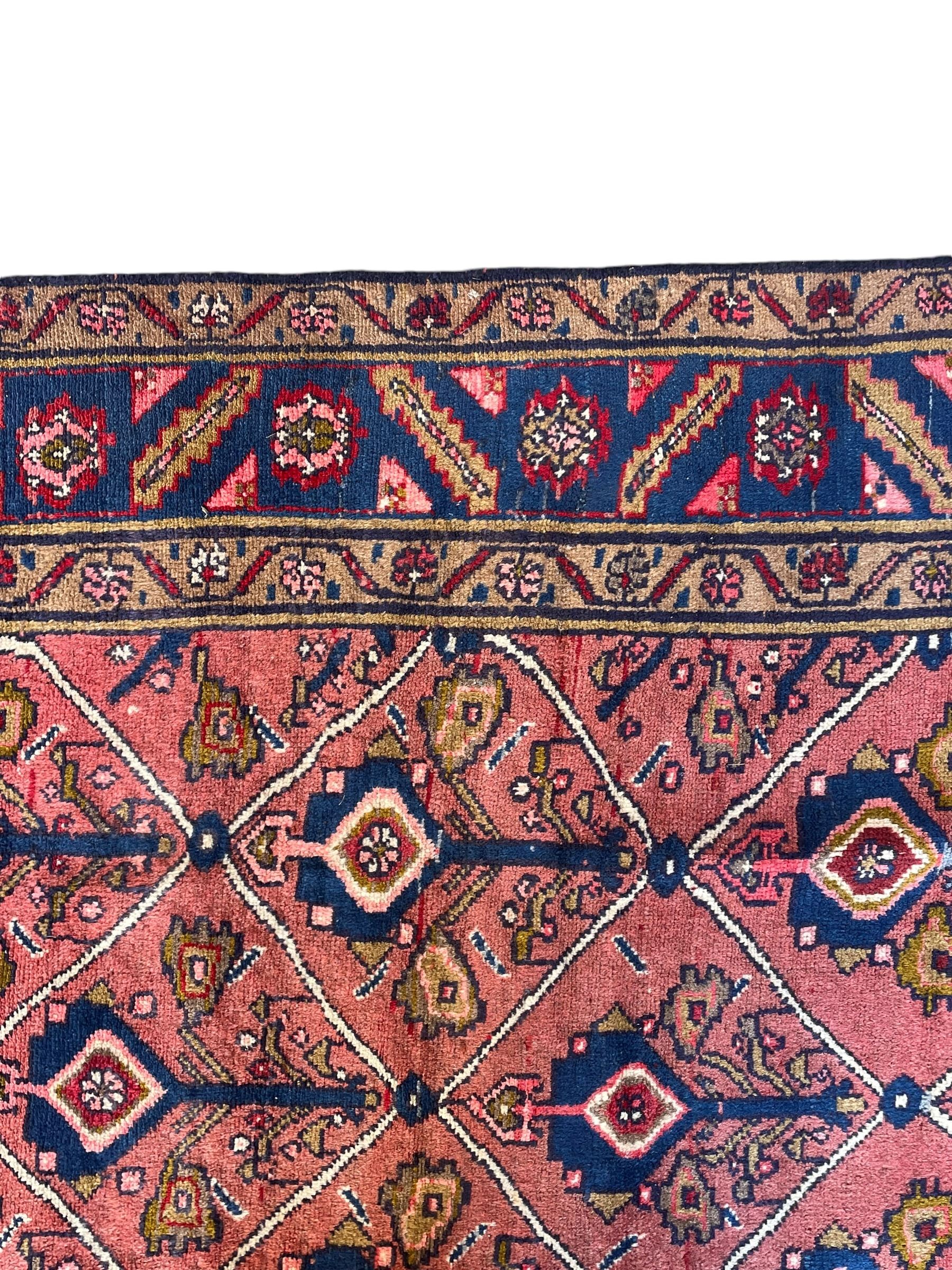 Persian Ardakan crimson ground rug, the field divided by lattice and decorated with stylised tree of life motifs, the border decorated with geometric flower heads, within guard stripes 