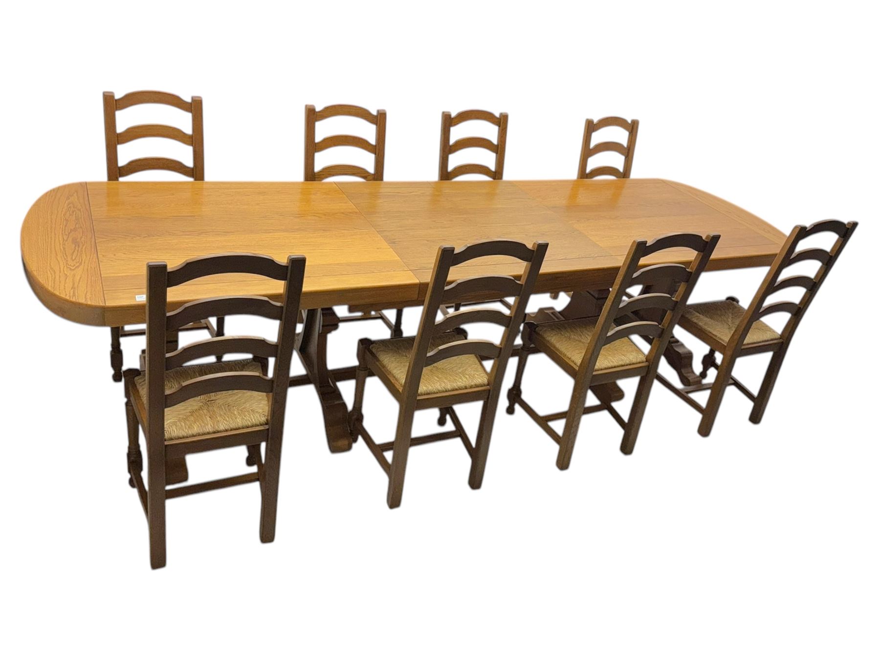 Oak extending dining table with elegant scrolled shaped double pedestal base and scrolled feet; together with a set of eight ladder back chairs with rush seats ((9) table closed 228x95x79cm chairs 106x38x44cm 