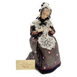 Anna Meszaros Hungary - hand made needlework figurine 'Old Lady' seated on a stool wearing a lace trimmed black/white/red floral full length dress and hat, working on a piece of lace H30cm  Auctioneer's Note: Anna Meszaros came to England from her native Hungary in 1959 to marry an English businessman she met while demonstrating her art at the 1958 Brussels Exhibition. Shortly before she left for England she was awarded the title of Folk Artist Master by the Hungarian Government. Anna was a gifted painter of mainly portraits and sculptress before starting to make her figurines which are completely hand made and unique, each with a character and expression of its own. The hands, feet and face are sculptured by layering the material and pulling the features into place with needle and thread. She died in Hull in 1998.