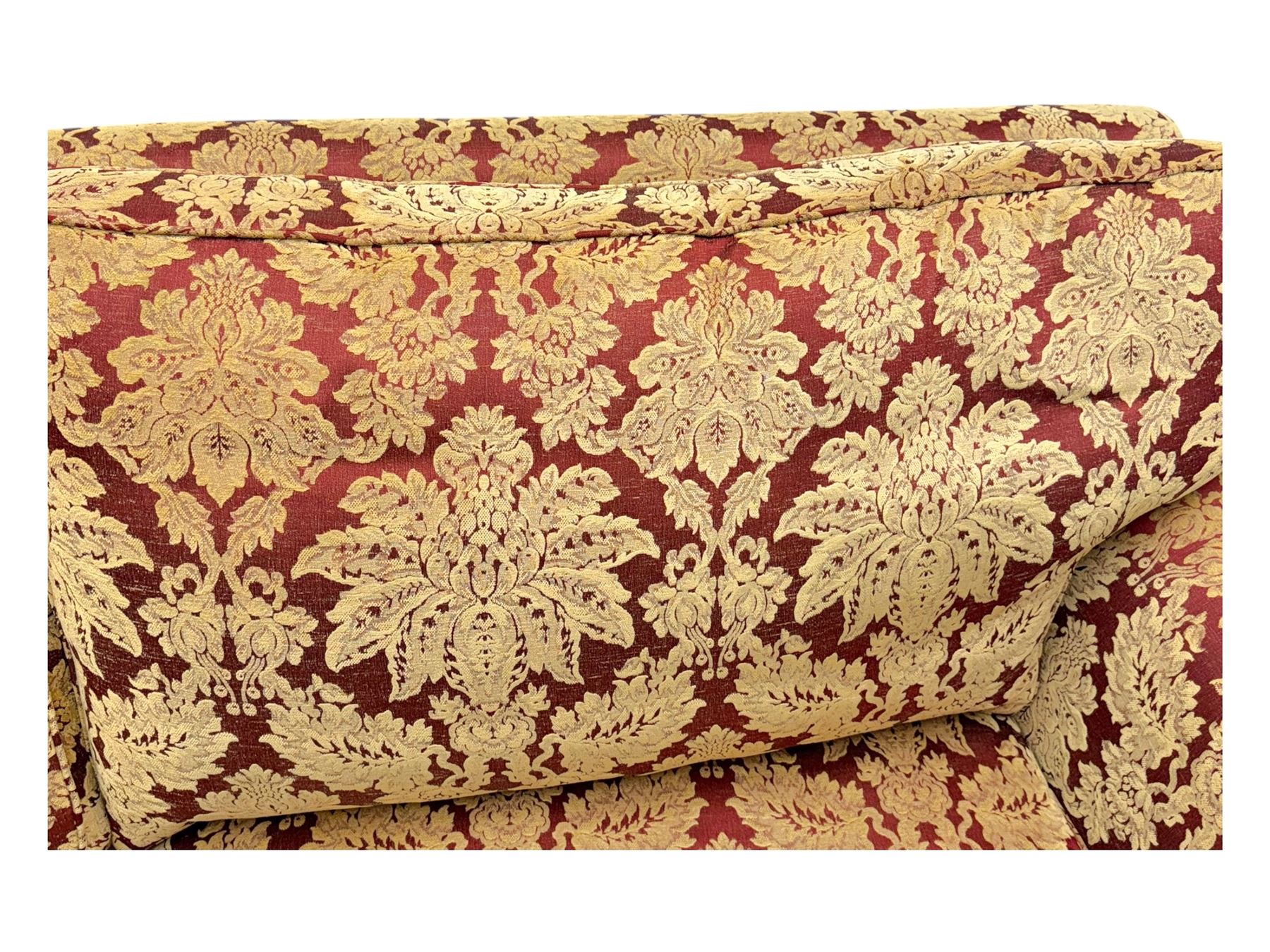 Duresta - pair of Grande three-seat sofas, traditional shaped with rolled arms and upholstered loose cushions, in red ground fabric with raised gold foliate pattern, on turned feet with brass castors 