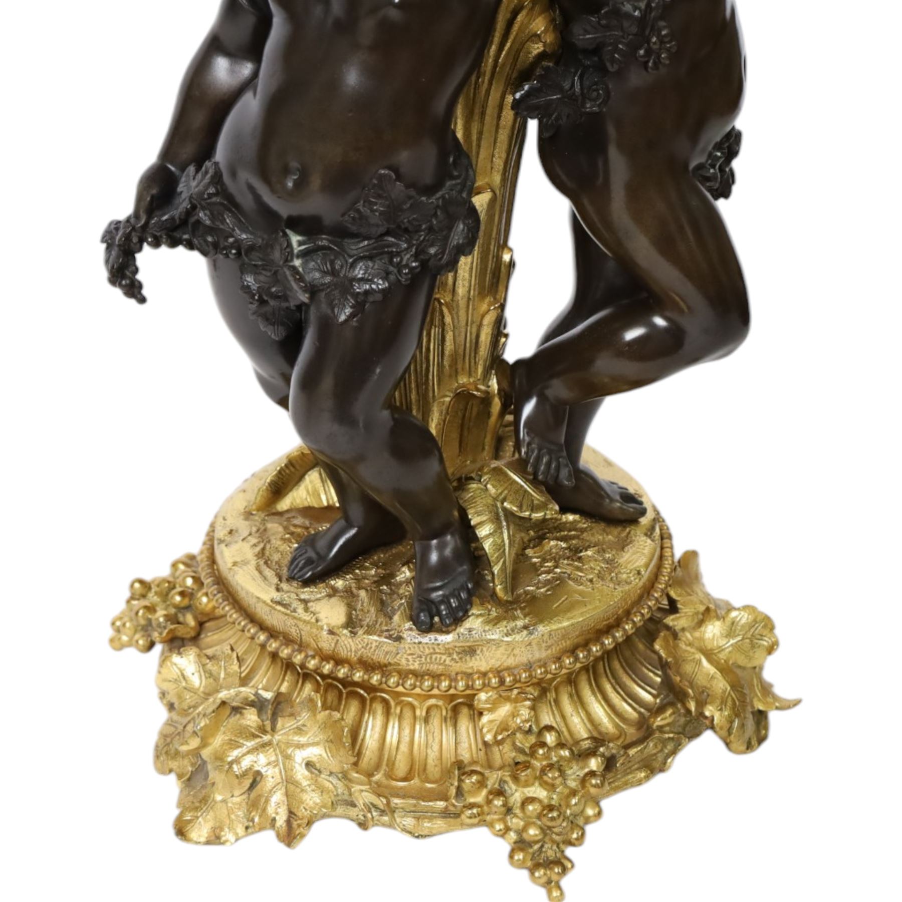 Louis XVI style gilt table lamp, the central column decorated with acanthus leaves, surrounded with three putti with vine leaf crowns, upon a circular base adorned with grape and vines, with shade, H64cm