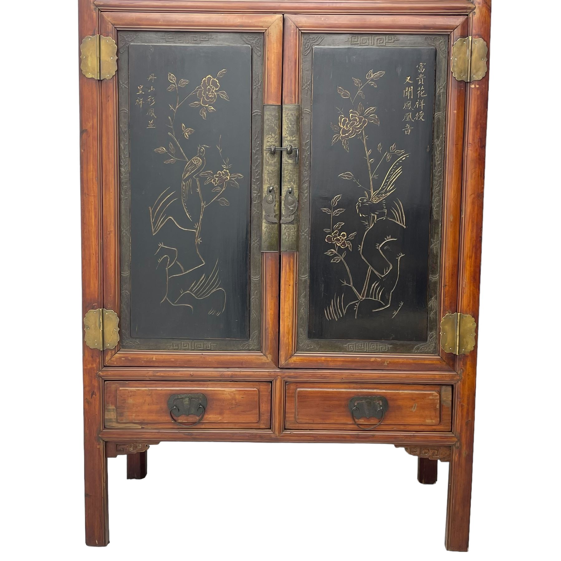 Late 19th century Chinese Qing dynasty red and black lacquered wood cabinet,  Fujianese province, upper cupboard enclosed by two doors with relief carved and gilt panels depicting figures behind glass, the large cupboard enclosed by two panelled doors carved with trailing foliate branches and birds, inscribed with Chinese characters, to the left ‘The red mountains are in the shape of Phoenixes and appear auspicious’ and to the right, ‘Wealth and honour are given by flowers and I hear the sound of the phoenix', fitted with two drawers, on square supports with carved brackets 