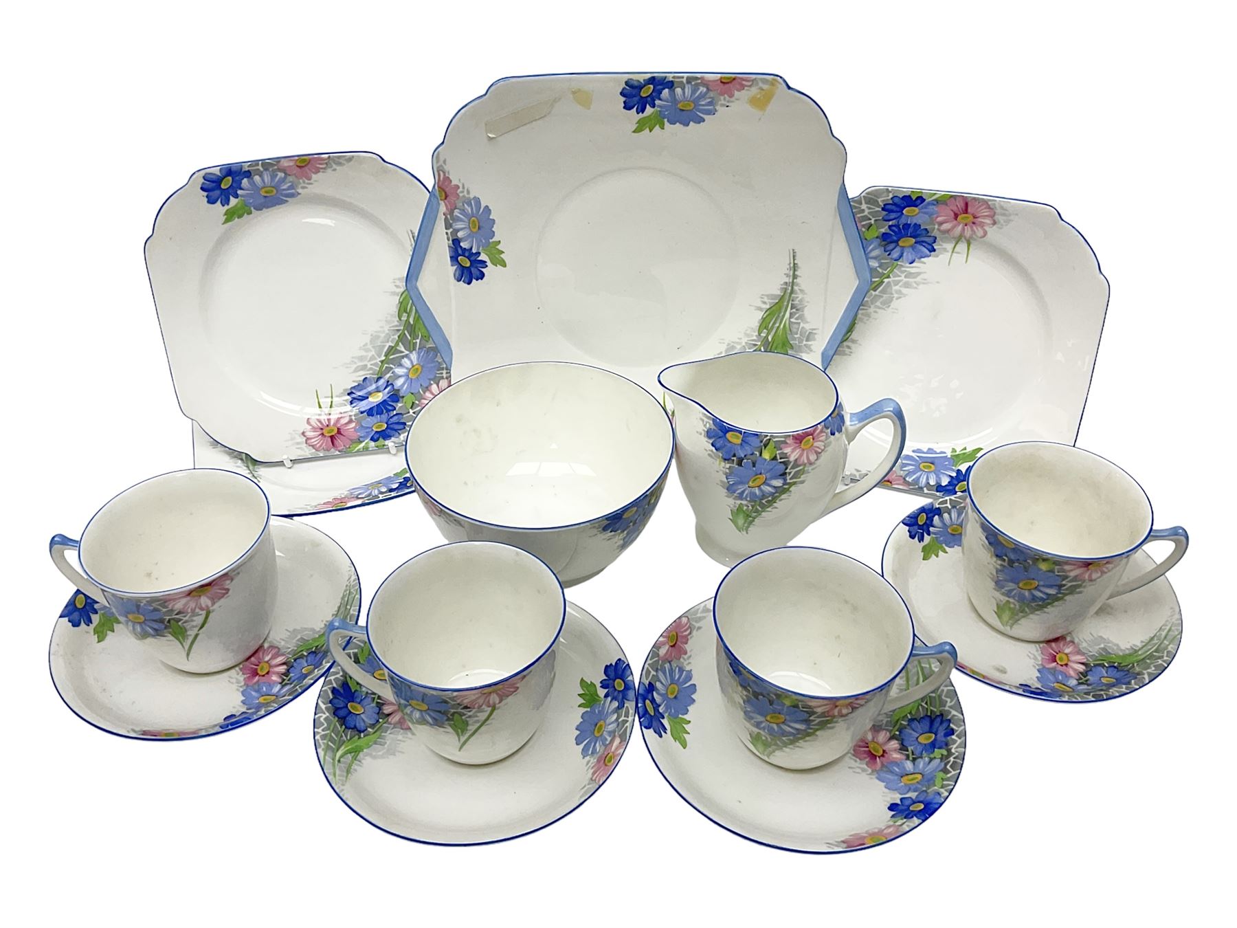 Shelley Strand shaped tea wares, decorated with blue and pink daisies upon a white ground, comprising four teacups, four saucers, three tea plates, milk jug, sugar bowl and cake plate, all with printed green mark beneath and painted pattern no 12216
