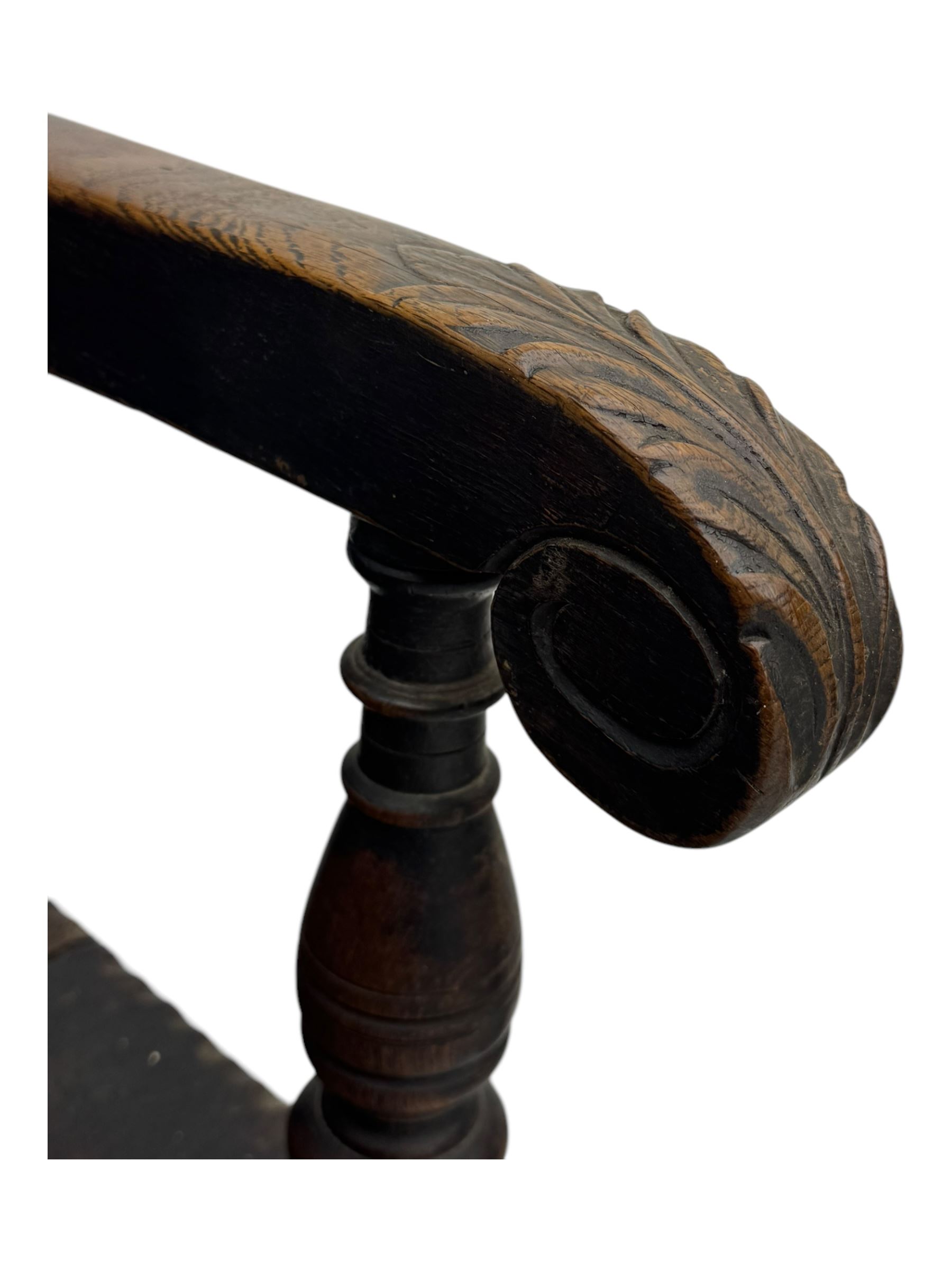 Late 19th century Jacobean revival carved oak armchair, the tall back with arched cresting featuring a stylised foliate mask, flanked by carved scrolls, relief carved panel depicting symmetrical foliage, downscrolled arms, on turned front supports united by stretchers