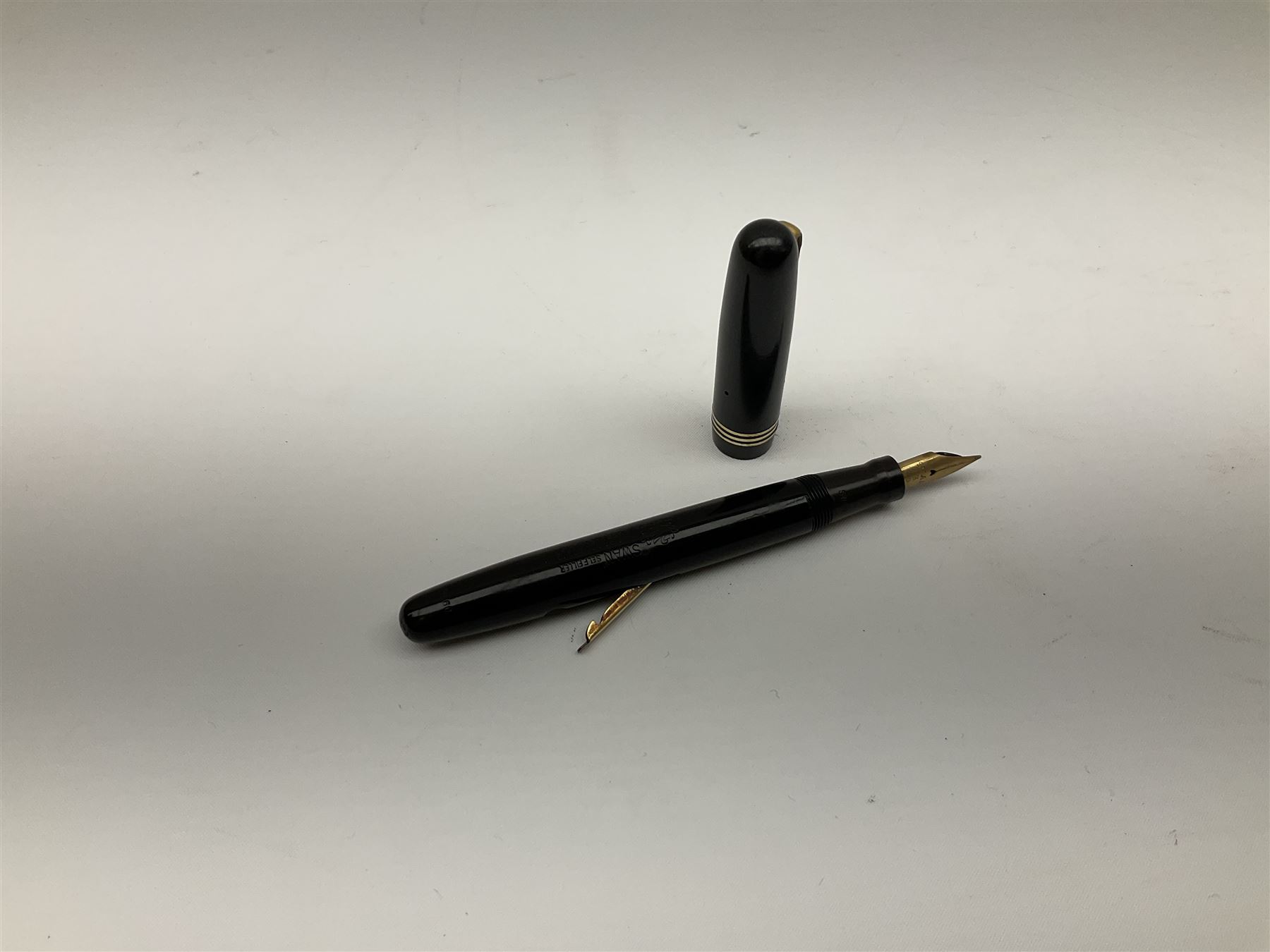 Vintage Swan Mabie Todd lever fill fountain pen in coral red, the nib a/f marked 14K, together with two further vintage Swan Mabie Todd fountain pens, the first example with lever fill, the other leverless, each with black body, one with nib marked 14ct, (3) 