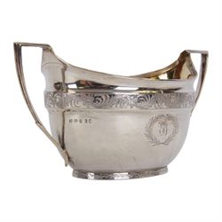 George III silver three piece tea service, comprising teapot with ivory scroll capped curved handle and ivory finial to the hinged cover, twin handled open sucrier with gilt interior, and cream jug with gilt interior, each of oval form with rounded sides, the bodies engraved with central monogram within a seaweed wreath, between engraved foliate bands, hallmarked John Emes, London 1801, teapot including handle H17cm

This item has been registered for sale under Section 10 of the APHA Ivory Act