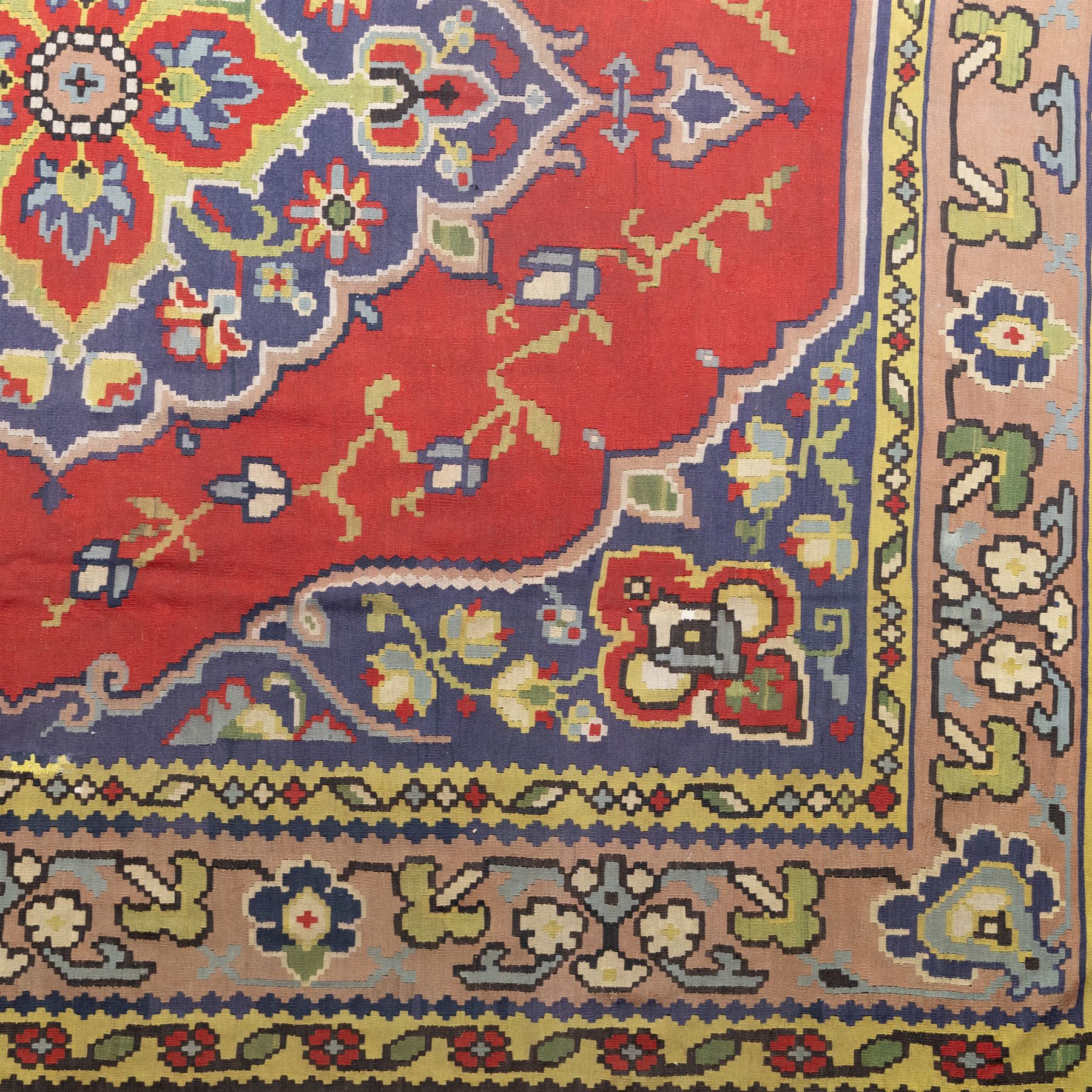 Turkish Malatya type flatwoven rug, decorated with a red medallion field, stylised floral motifs and blue corner panels, enclosed by beige foliate border and outer floral guard band