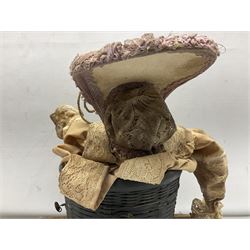 Modern reproduction automaton in the form of a baby doll in a basket clothed in Victorian style lace bloomers and frilled bonnet; clockwork action; on raised platform; with French paper label on base, 29cm wide,
