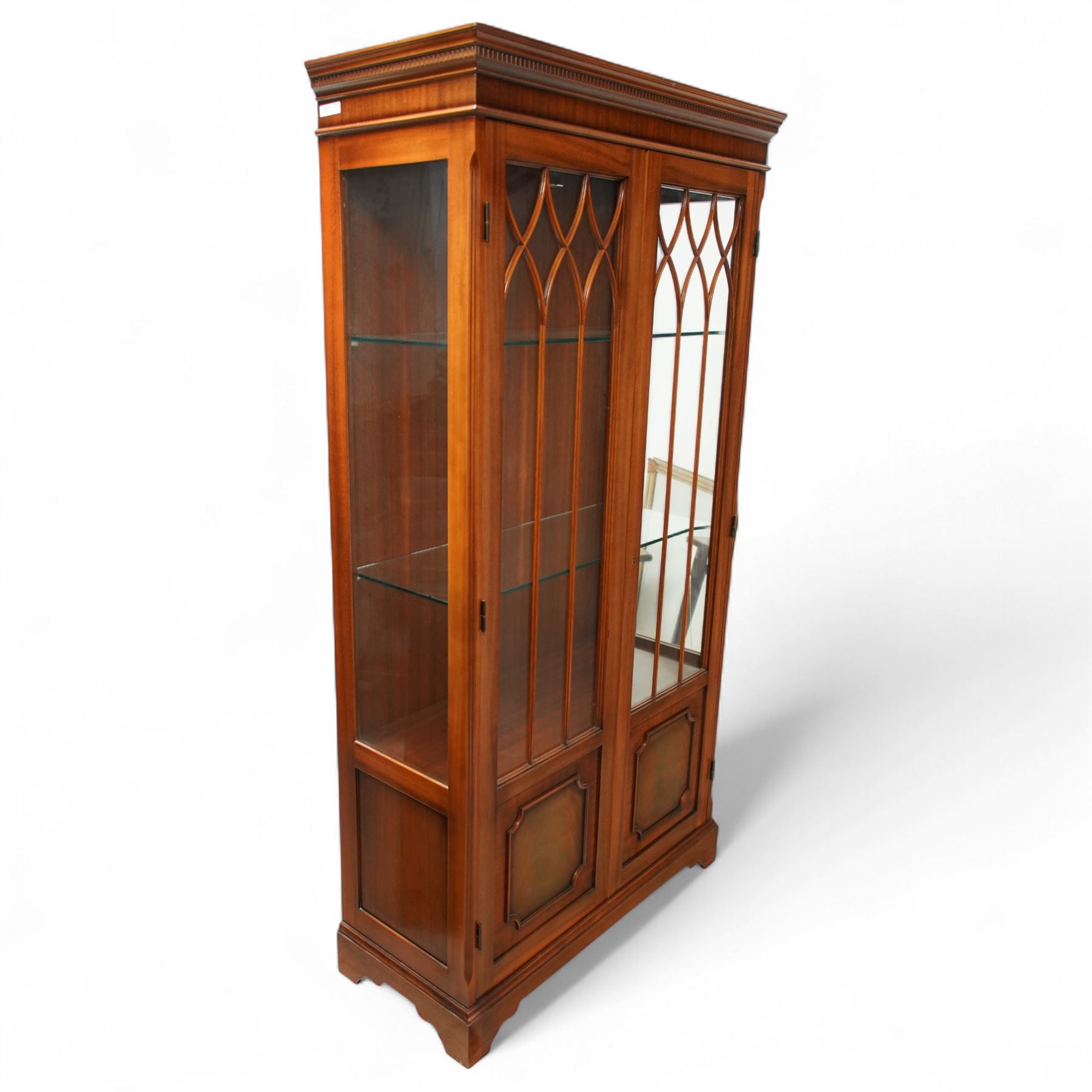 20th century Georgian design mahogany display cabinet with illuminated interior, dentil moulded cornice over twin astragal glazed doors enclosing glass shelves, lower panelled cupboard doors, on shaped bracket feet