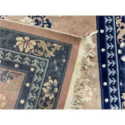 Chinese washed woollen peach ground rug, indigo borders and trailing foliate decoration, central medallion decorated with flowerheads 