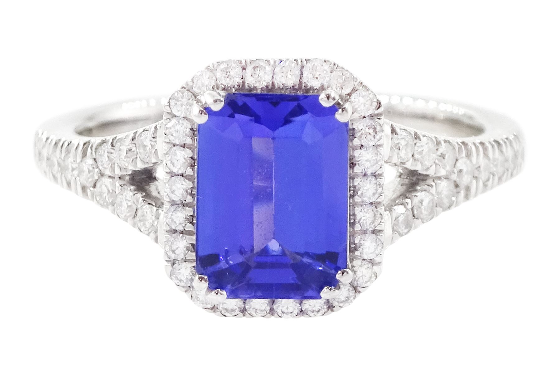 Platinum tanzanite and diamond cluster ring, single emerald cut tanzanite of approx 1.75 carat, with round brilliant cut diamond surround and split diamond set shoulders, signed Rhapsody, hallmarked, total diamond weight approx 0.20 carat