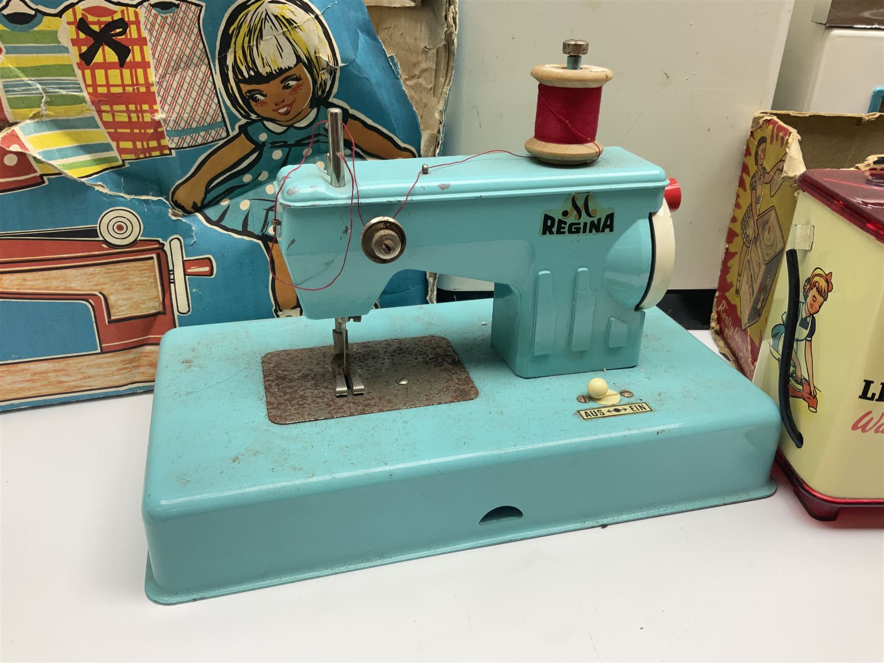 Six toy kitchen appliances - Casdon battery operated cooker; Mettoy Hoover washer; Chad Valley Hoovermatic washer; Wells Brimtoy tin-plate clockwork washer; and two Morphy Richards irons; together with a continental child's Regina sewing machine; all boxed (7)