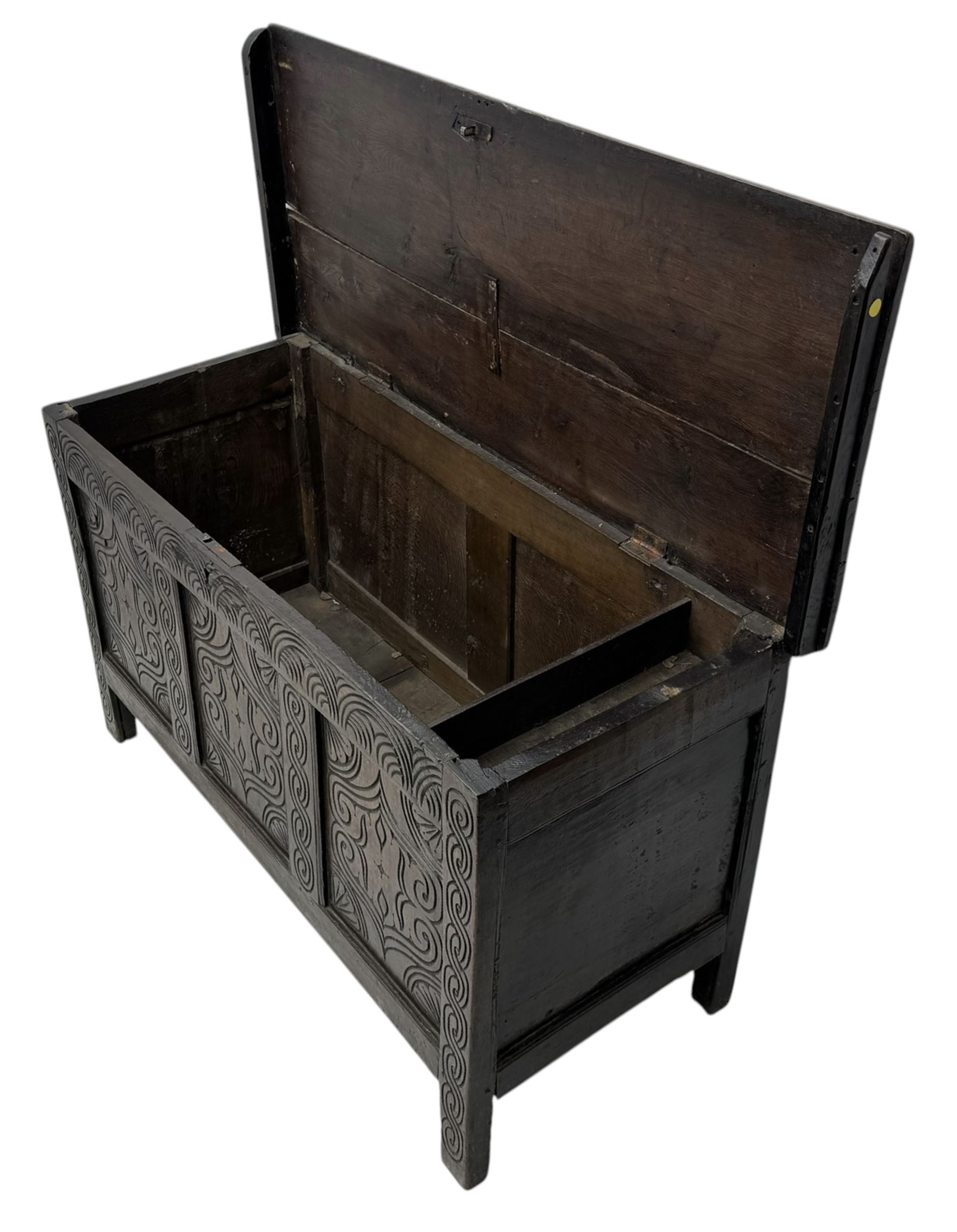 English carved oak coffer, hinged rectangular lid with indented side edges, internal candle-box, front with three-panel front with decorative carvings, raised on stile feet, circa 1700
