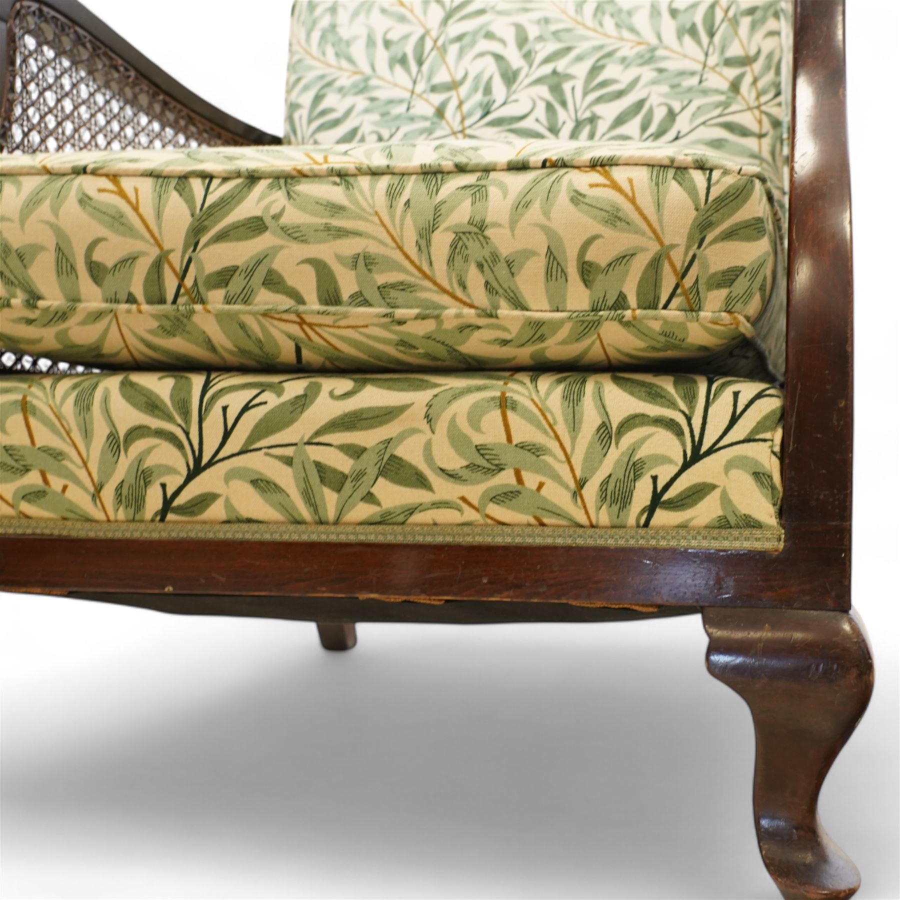 Edwardian stained beech Bergère armchair, with double cane sides and back, with the apron seat and cushion seat and back cushion, upholstered in a William Morris Willow Bough fabric, supported on cabriole legs with pad feet 