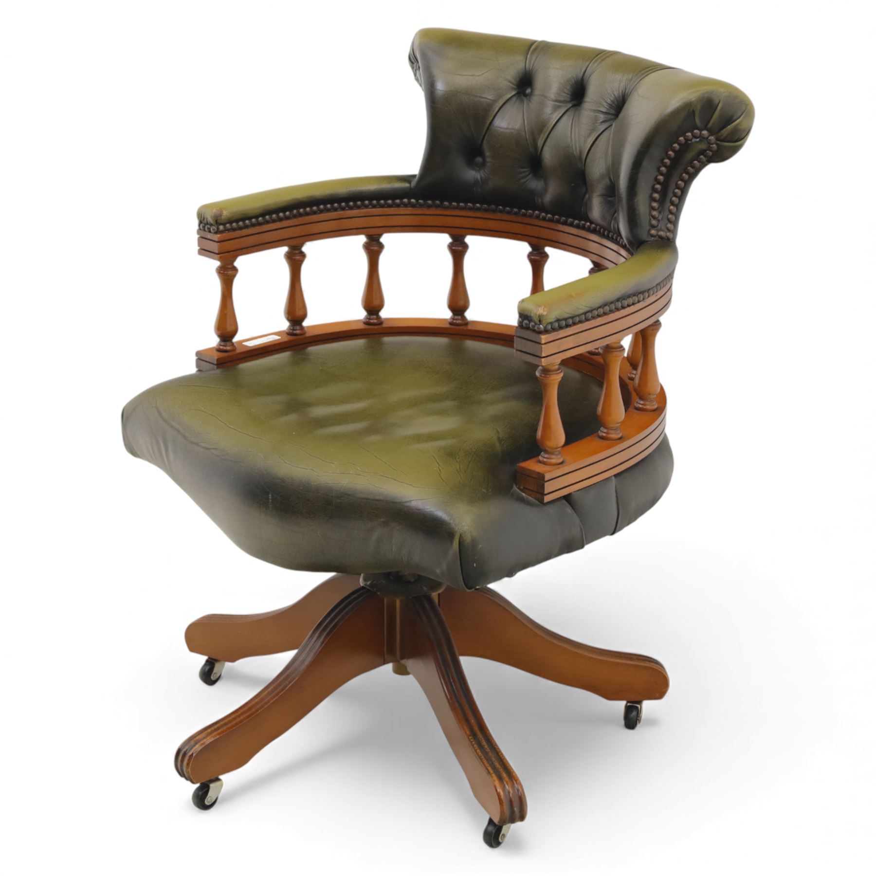 Late 20th century swivel captain’s desk chair, green buttoned vinyl upholstered back and seat with brass stud edging, the spindle gallery over a rotating base with five splayed supports on castors