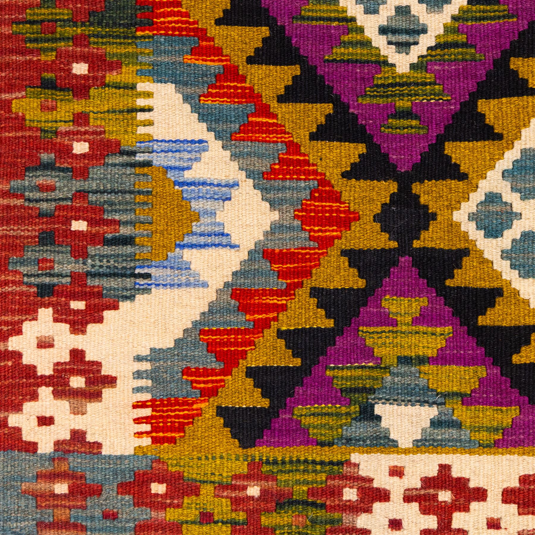 Afghan Maimana flatweave kilim, central field features large bold nested diamond motifs and stylized geometric lozenge patterns on olive purple, blue, and green tone ground, border stripe in teal ground, and fringe