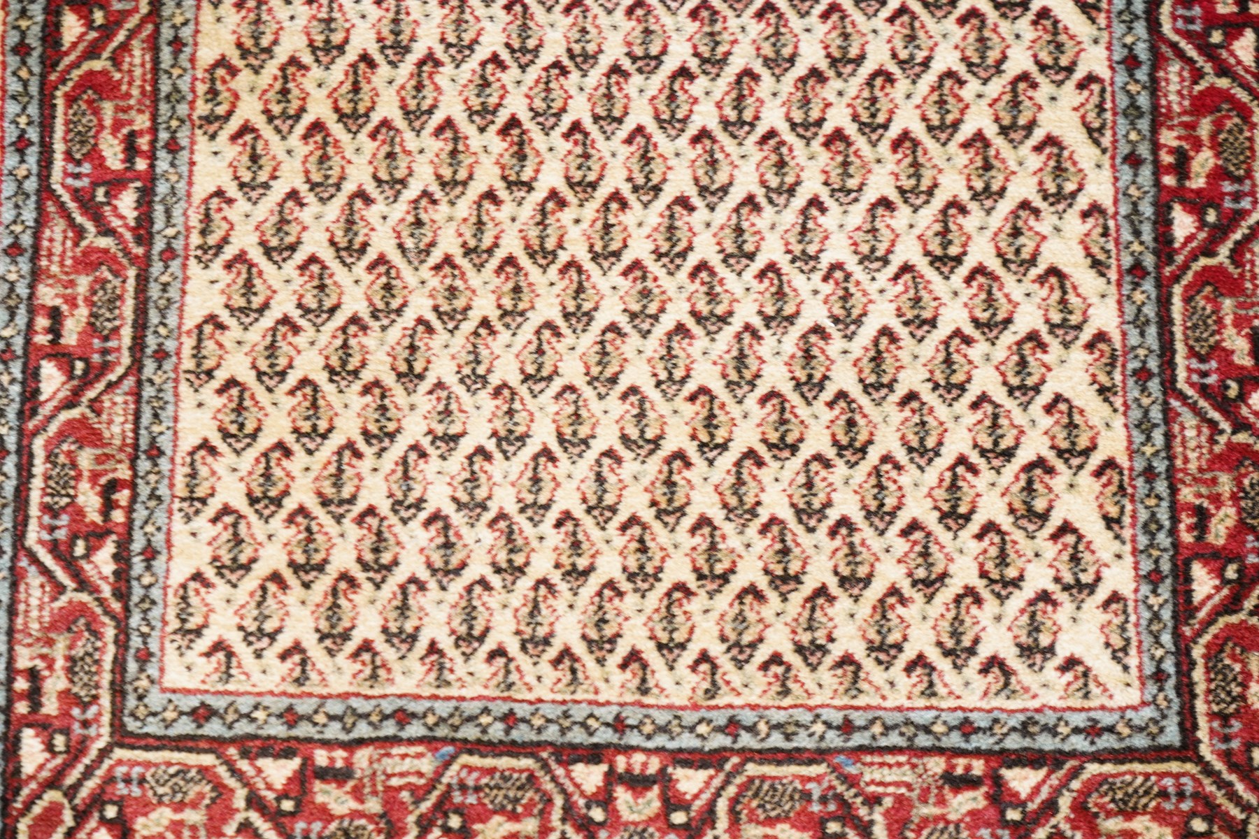 Collection of four Persian rugs, comprising a Saraband ivory ground rug with all-over boteh field and multiple borders; a crimson ground Hamadan type rug with all-over stylised floral and geometric motifs; a floral medallion prayer rug with dark field and ivory spandrels; and a Hamadan peach ground rug with repeating stylised flowering plants and dark multiple borders, largest 83cm x 142cm