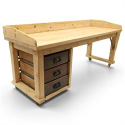 Mid-20th century pitch pine and beech bakers table, three quarter galleried rectangular plank top, three drawer pedestal with iron handles and runners, square supports with iron spandrel, raised on castors 