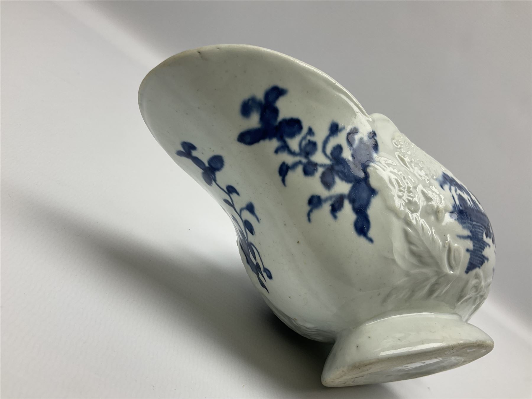 Large 18th century Lowestoft sauce boat, circa 1770, the body decorated with Hughes type floral moulding, and painted in underglaze blue with an Oriental landscape, and foliate sprigs, L23cm