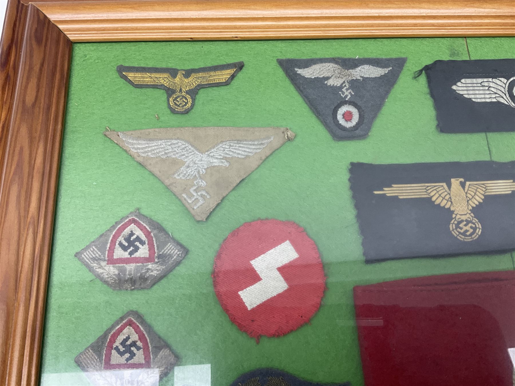 Framed display of thirty-four WWII German cloth badges including Luftwaffe pilot, Paratrooper, Afrikakorps cuff title, sleeve insignia for 'SS' Foreign Volunteers, various breast eagles including Luftwaffe, Army etc, RAD badges, Party Armband, rank and trade insignia, cap insignia etc; 40 x 50cm in modern pine frame