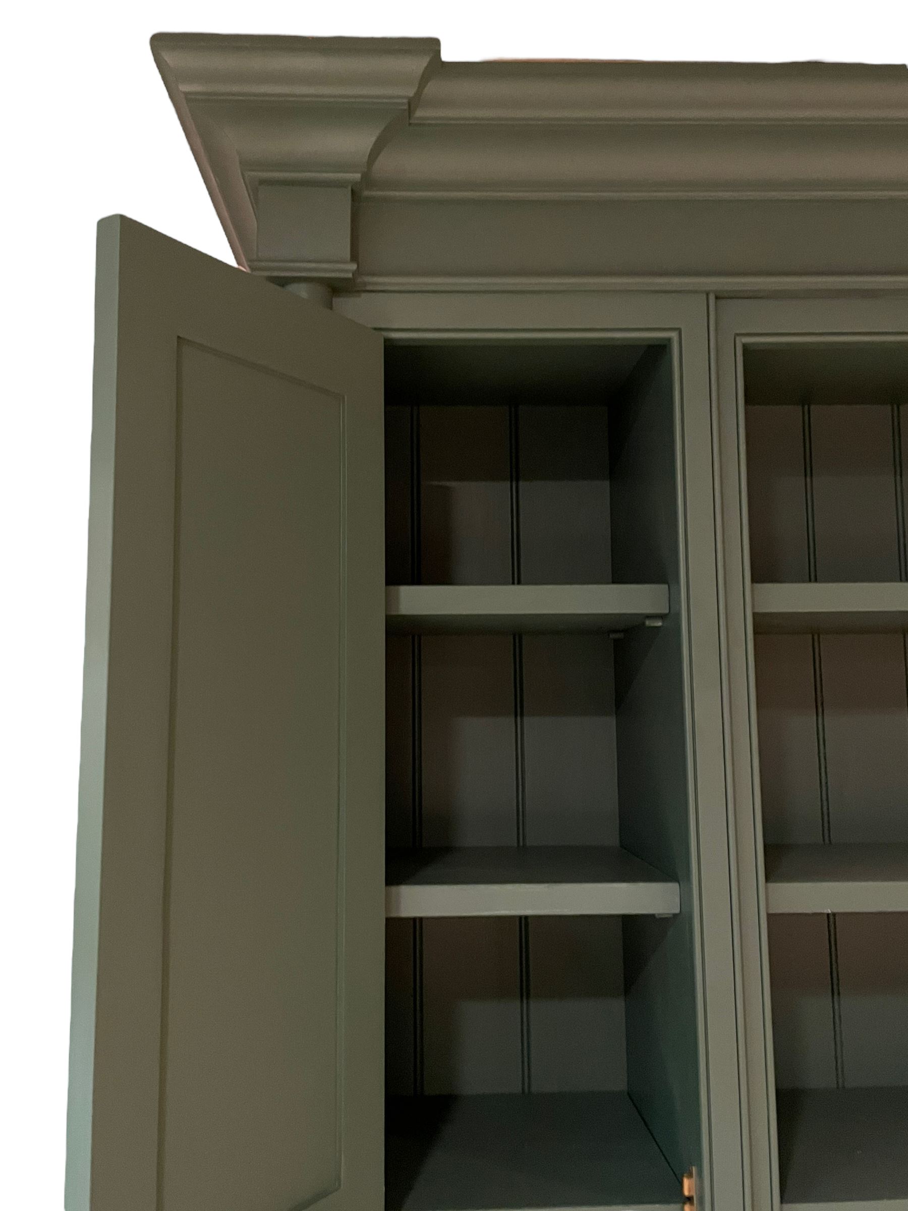 Large contemporary teal green painted kitchen dresser, projecting cornice over three open shelves flanked by cupboard with five spice drawers below, the base fitted with four assorted drawers, raised on turned vasiform supports united by undertier