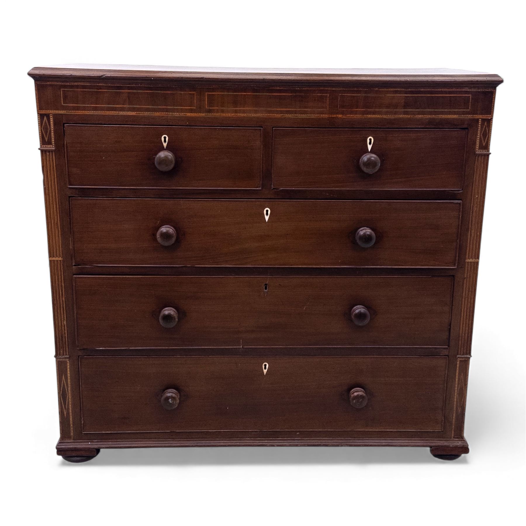 Early 19th century mahogany chest of drawers, the rectangular top with boxwood line inlay above two short and three long graduating drawers, each with turned wooden knobs and bone escutcheons, flanked by fluted uprights with diamond inlaid panels, on shaped bracket feet