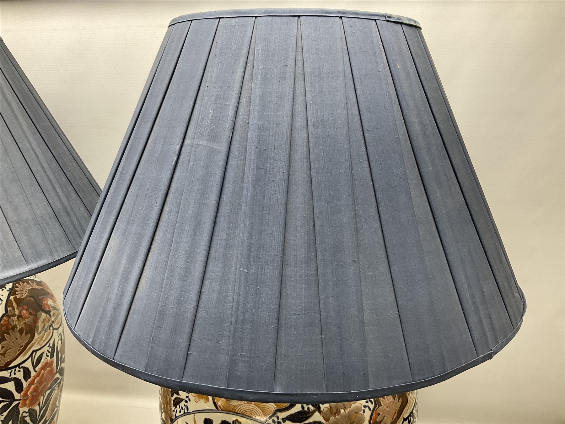 Pair of large and impressive 20th century Japanese Imari table lamps, each of ovoid form, decorated in the Imari palette with roundels containing flowering urns, and shaped panels of birds, set against a white ground decorated with blossoming peonies, lamp base (not including fixtures) H56.5cm overall including shade H89cm