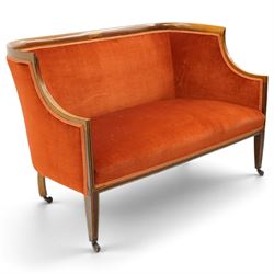Edwardian inlaid mahogany tub two seater settee, traditional shape with satinwood stringing, upholstered in crimson fabric with sprung seat, on square tapering supports with castors