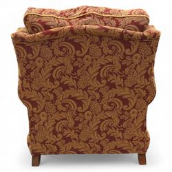 Duresta – pair of armchairs, upholstered in red and gold damask fabric with piped edges, scroll arms and loose feather-filled cushions, raised on turned wooden feet with brass castors
