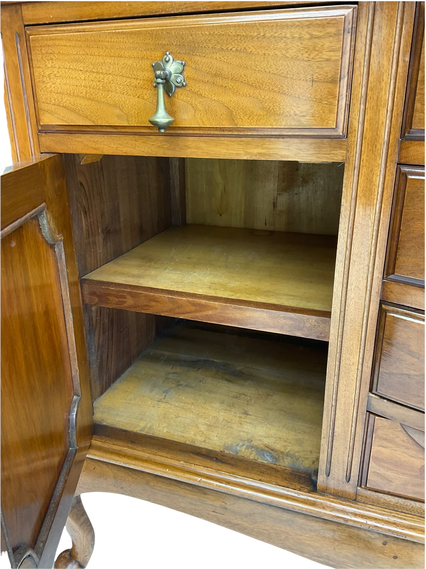 Late Victorian walnut mirror back sideboard or dresser, the raised back fitted with two curved and lead glazed cabinets, central arched bevelled mirror, the sideboard with break bowfront, fitted with six drawers and two cupboards, the cupboard doors panelled and carved with scrolls, shell and plant motifs, shaped apron with cabriole feet
