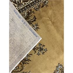 Persian design golden beige ground rug, the field with symmetrical scrolling foliate and floral designs, central floral medallion, bordered by a multi-layered band with floral and vine patterns in contrasting beige and dark brown tones