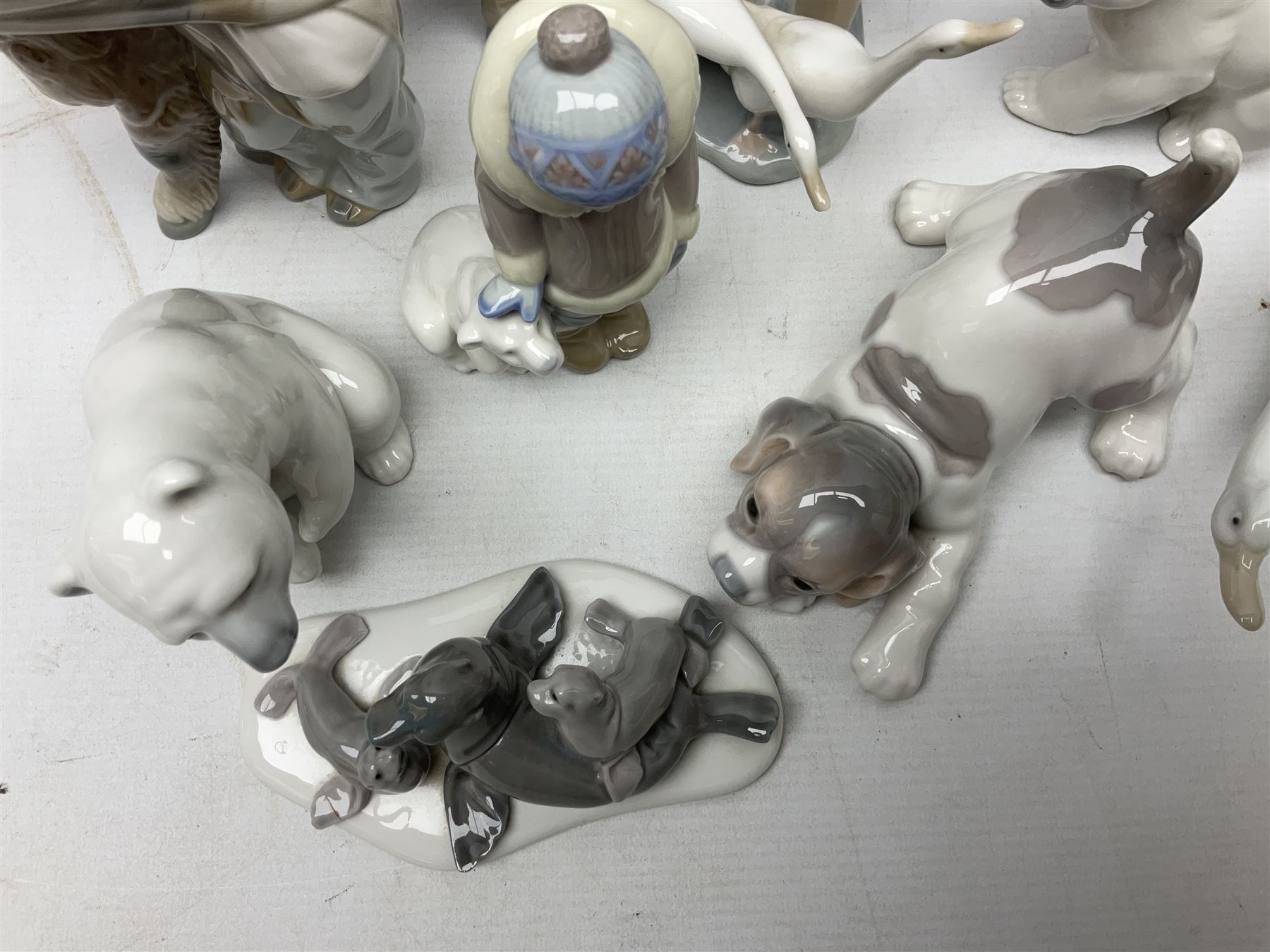 Seven Lladro figures, comprising Playful Puppy no 9135, Platero and Marcelino/Boy Hugging Donkey no 1181, Mini Seal Family no 5318, Attentive Polar Bear no 1207, Seated Polar Bear no1209, Eskimo Boy with Pet no 5238 and Girl with Geese no 1035, together with Nao goose