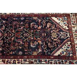 North West Persian Hamadan hand-knotted runner, indigo field with an all-over herati inspired lattice issuing from a central axis with stylized palmettes, rosettes and angular vinery, enclosed by stepped triangular spandrels with ivory reserves, broad ivory main border of stylized flowers and geometric devices, flanked by reciprocal guard stripes, cotton fringe ends 