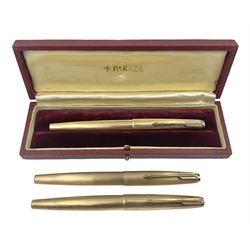 Three rolled gold Parker fountain pens, comprising an example with a gold nib marked 14K 585 and barrel with a shell stamp, a Parker 61 fountain pen with inset gold arrow to the nib, and another similar, all with striated decoration and arrow clips to the caps, L13cm, one with box